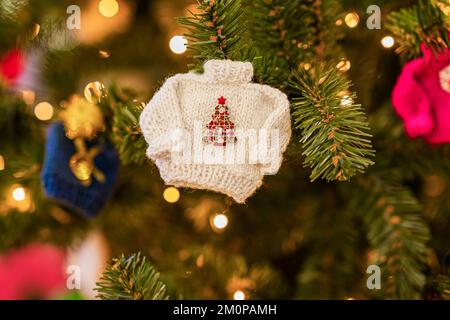 Weihnachtsbaumschmuck in Form von Strickpullover, Bokeh-Girlanden. Frohes neues Jahr und Weihnachtskarte, Winterurlaub Stockfoto