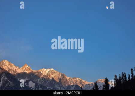 An einem kalten Wintertag in Sonamarg, etwa 100kms km nordöstlich von Srinagar, der Sommerhauptstadt von Jammu und Kaschmir, erhebt sich der wachsende Gibbuus-Mond über den schneebedeckten Bergen. Stockfoto