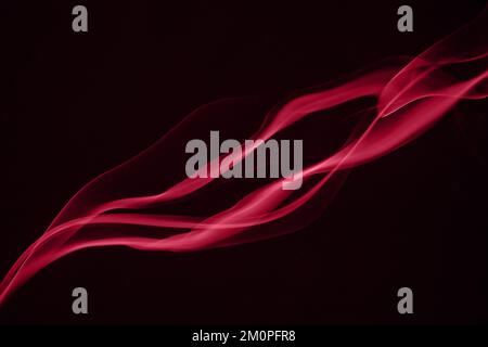 Rote Rauchspuren auf schwarzem Hintergrund. Farbe des Jahres 2023 - Viva Magenta Stockfoto