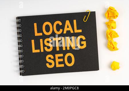 Geschäftskonzept. Auf weißem Hintergrund befindet sich eine Markierung, ein Ausrufezeichen aus Papier und ein Notizbuch mit der Aufschrift „LOCAL LISTING SEO“ Stockfoto