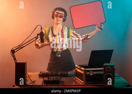 Weibliche Mixer-Werbung Karton Sprechblase im Studio, zeigt isolierte Textnachrichten Pappe. Junger dj-Darsteller mit Plakatvorlage mit Coyspace, Plattenspieler aus Vinyl. Stockfoto