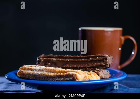 Typisch argentinische Churros mit einer Tasse Kaffee auf dunklem Hintergrund. Stockfoto