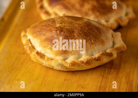 Extreme Nahaufnahme von gebackenen argentinischen Empanadas auf einem Brett. Stockfoto