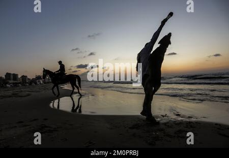 Gaza, Palästina. 07.. Dezember 2022. Ein Palästinenser trainiert seinen Hund bei Sonnenuntergang entlang der Küste westlich von Gaza City. (Foto: Mahmoud Issa/SOPA Images/Sipa USA) Guthaben: SIPA USA/Alamy Live News Stockfoto