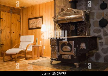 Antiker gusseiserner Holzofen im Untergeschoss, Familienzimmer im 1978 erbauten Nachbau des alten Canadiana Cottage-Stil Holzhaus und Feldsteinhaus. Stockfoto