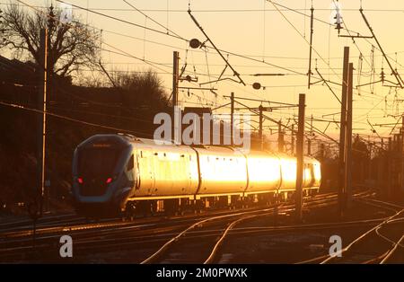 TransPennine Express emu, 397009, Durchfahrt durch Carnforth auf der West Coast Main Line am 7.. Dezember 2022 bei Sonnenuntergang mit Sonnenlicht vom Zug. Stockfoto