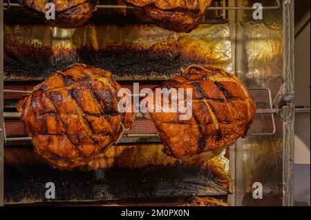 BONN, DEUTSCHLAND - 6. DEZEMBER 2022: Nahaufnahme von Prager Schinken, der auf einem Spieß geröstet wird Stockfoto