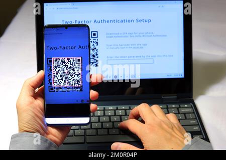 Eine Person scannt einen QR-Code mit der Google Authenticator App auf ihrem Smartphone, um eine zwei-Faktor-Authentifizierung 2FA für sichere Anmeldungen einzurichten Stockfoto