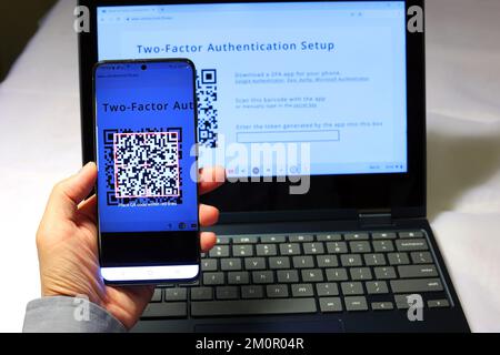 Eine Person scannt einen QR-Code mit der Google Authenticator App auf ihrem Smartphone, um eine zwei-Faktor-Authentifizierung 2FA für sichere Anmeldungen einzurichten Stockfoto