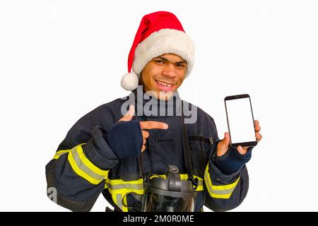 Feuerwehrmann in Santa hat hält Smartphone in der Hand Stockfoto