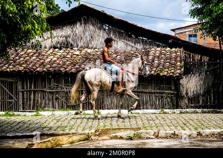 Aratuipe, Bahia, Brasilien - 31. August 2018: Junger Mann auf dem Pferderücken pässt vor einer Fassade eines Keramiktopf herstellenden Ladens in der Stadt Aratuipe, Ba Stockfoto