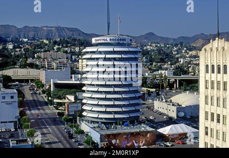 Das klassische Capitol Records Gebäude mit dem historischen Hollywood-Schild auf den Hügeln im Hintergrund in Hollywood, CA, aus der Vogelperspektive Stockfoto