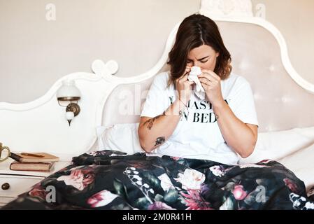 Ich schätze, ich muss einfach im Bett bleiben. Eine Frau, die zu Hause an einer Erkältung leidet. Stockfoto
