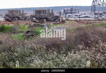 Gaza, Palästina. 07.. Dezember 2022. In der Nähe israelischer Bagger und Bulldozer ist ein israelischer Merkava-Kampfpanzer stationiert, der die Überreste des Karni-Handelsübergangs in der Nähe der Grenze zu Gaza abriss, als Israel beschloss, eine Sicherheitsbarriere am Standort des seit langem stillgelegten Terminals zu erweitern. Kredit: SOPA Images Limited/Alamy Live News Stockfoto