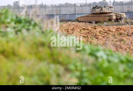 Gaza, Palästina. 07.. Dezember 2022. In der Nähe israelischer Bagger und Bulldozer ist ein israelischer Merkava-Kampfpanzer stationiert, der die Überreste des Karni-Handelsübergangs in der Nähe der Grenze zu Gaza abriss, als Israel beschloss, eine Sicherheitsbarriere am Standort des seit langem stillgelegten Terminals zu erweitern. Kredit: SOPA Images Limited/Alamy Live News Stockfoto