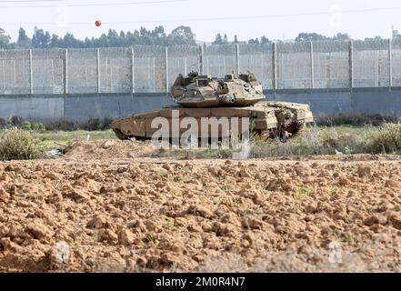 Gaza, Palästina. 07.. Dezember 2022. In der Nähe israelischer Bagger und Bulldozer ist ein israelischer Merkava-Kampfpanzer stationiert, der die Überreste des Karni-Handelsübergangs in der Nähe der Grenze zu Gaza abriss, als Israel beschloss, eine Sicherheitsbarriere am Standort des seit langem stillgelegten Terminals zu erweitern. Kredit: SOPA Images Limited/Alamy Live News Stockfoto