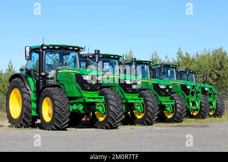 Eine Reihe von fünf neuen John Deere 6155R-Traktoren, die an einem sonnigen Tag im Frühherbst auf einem Hof geparkt wurden. Lieto, Finnland. 22. September 2022. Stockfoto
