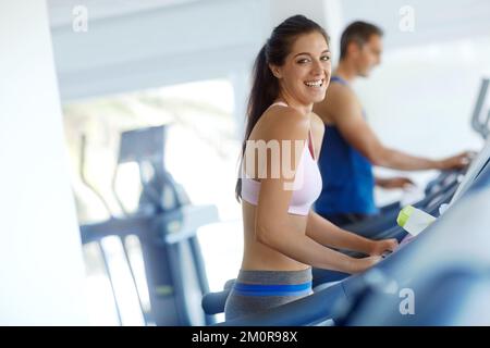 Auf dem Laufband. Ein junger Mann und eine junge Frau, die im Fitnessstudio auf Laufbändern trainieren. Stockfoto