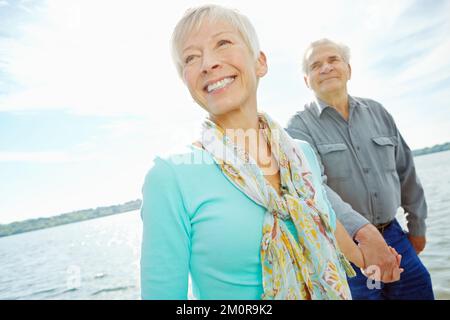 Lass uns gehen, Schatz. Eine attraktive Seniorin, die ihren Mann an der Hand hält und ihn über den Steg führt. Stockfoto
