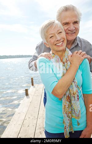 Wir waren immer füreinander da. Ein liebevolles Seniorenpaar, das sich gegenseitig auf einem Steg hält. Stockfoto