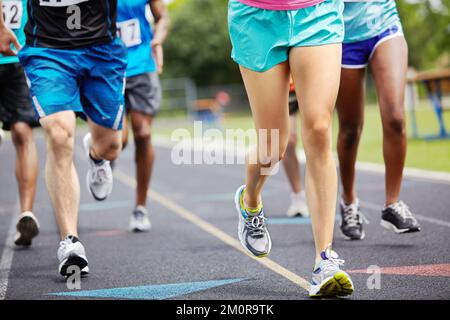 Um den Siegertitel laufen. Kürzere Nahaufnahme der Beine von Sportlern während eines Rennens. Stockfoto