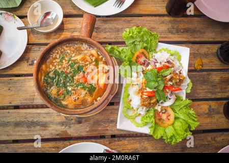 Tisch mit thailändischen Gerichten wie Curry, Eier, gedünsteter Tintenfisch, Zitrone. Stockfoto