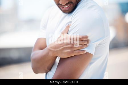 Nahaufnahme eines Mannes, der während seines Workouts im Freien seinen Arm hält und Schulterschmerzen hat. Gemischter männlicher Sportler fühlt sich durch A unwohl Stockfoto