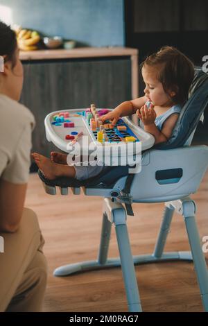 Ein kleines Mädchen lernt, Zahlen zu erkennen, die am Babytisch sitzen. Konstruktor. Lernen, lernen, Grundschulkinder Konzept. Stockfoto