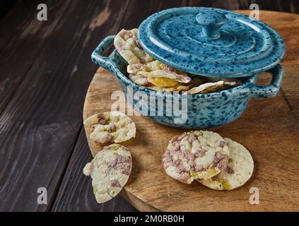 Puff Chips mit Kichererbsen, Erbsen und Bohnen in einer Glasschüssel mit Deckel auf Holzhintergrund. Stockfoto