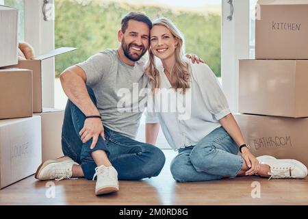 Porträt eines Paares, das zusammenzieht. Glückliches weißliches Paar, das mit Kisten in ein erworbenes Grundstück zieht. Ein Paar, umgeben von beweglichen Kisten. Jung Stockfoto