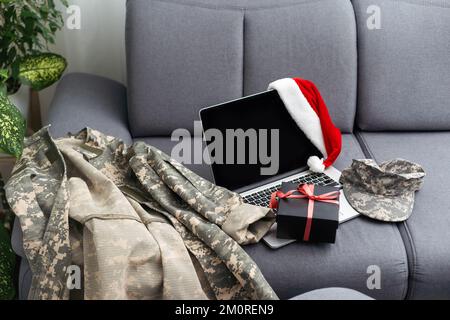 Militäruniform und Weihnachtsmannmütze mit Laptop. Das Konzept von Weihnachten und Neujahr. Stockfoto