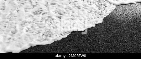 Kontrastierender weißer Schaum am schwarzen Strand von Lanzarote. Horizontales Banner Stockfoto