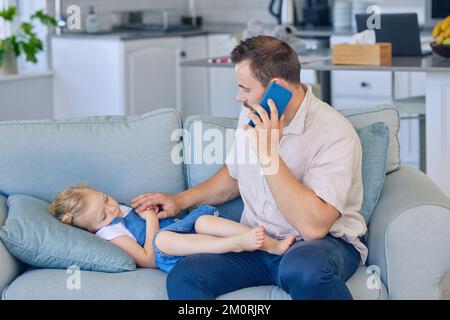 Krankes kleines Mädchen, das auf dem Sofa liegt, während Dad mit dem Handy den Arzt anruft. Besorgter Vater telefoniert mit einem Arzt, während er krank ist Stockfoto