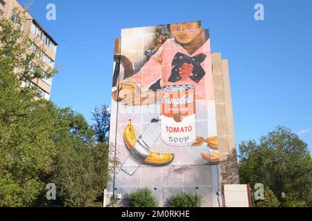 Ein riesiges gemaltes Wandgemälde am Ende eines großen Apartmentgebäudes, das eine Kombination aus Warhols Campbell's Tomatensuppe Dose, einer Banane und Val mit Klebeband darstellt Stockfoto