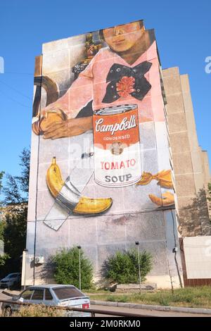 Ein riesiges gemaltes Wandgemälde am Ende eines großen Apartmentgebäudes, das eine Kombination aus Warhols Campbell's Tomatensuppe Dose, einer Banane und Val mit Klebeband darstellt Stockfoto