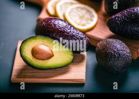 Frische Avocado- und Zitrusscheiben auf dem Schneidebrett. Avocado in zwei Hälften geschnitten Stockfoto