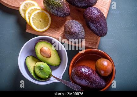 Frische Avocado und Tomaten in der Schüssel. Avocado- und Zitrusscheiben auf dem Schneidebrett Stockfoto