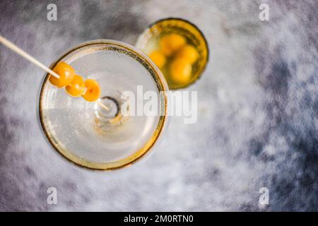 Blick von oben auf einen Wodka-Cocktail und einen Becher gefüllt mit gelben Glace-Kirschen Stockfoto