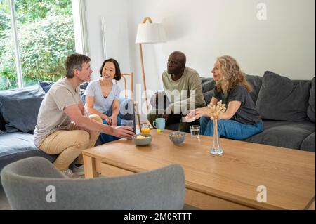 Porträt von zwei verschiedenen Paaren, die sich unterhalten, während sie drinnen einen Drink trinken Stockfoto