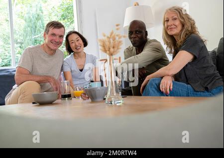 Porträt einer Gruppe von Seniorfreunden, die sich zu Hause amüsieren und die Kamera betrachten Stockfoto