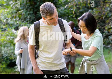 Two middle-aged male and female hikers stopping to look lady's fitbit Stock Photo