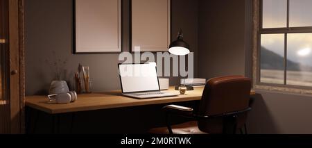 Seitenansicht eines modernen Arbeitsbereichs zu Hause mit Laptop-Modell, Licht von Tischleuchte und Zubehör auf Holztisch an der grauen Wand mit leerem rahmen Stockfoto