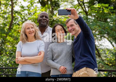 Porträt verschiedener Paare, die Spaß haben, während sie ein Selfie im öffentlichen Park machen Stockfoto