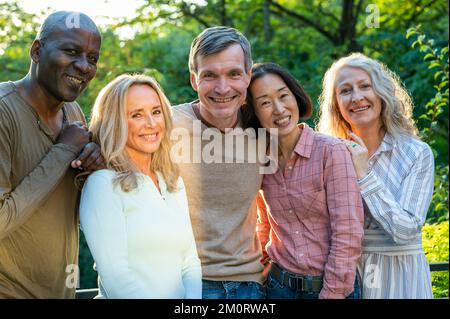 Gruppe von verschiedenen glücklichen älteren Freunden, die sich bei Sonnenuntergang für Fotos im Freien posieren Stockfoto