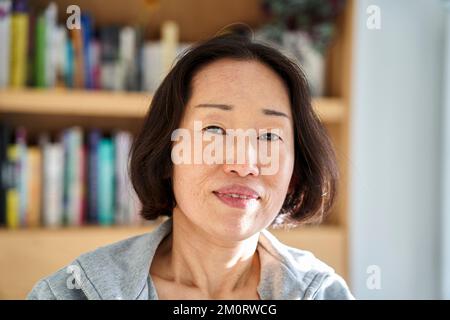Senior Asian woman looking at the camera while sitting indoors Stockfoto