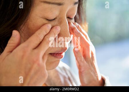 Close-up of senior Asian woman touching her face Stockfoto