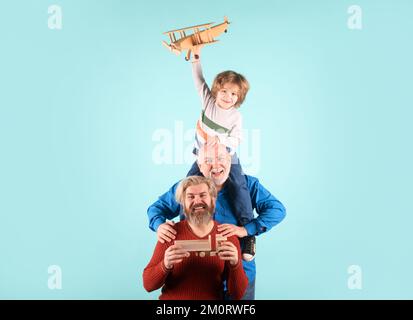 Der Junge Sohn mit dem Vater und der Großvater mit einem Spielzeugflugzeug spielen auf isoliertem Hintergrund. Stockfoto