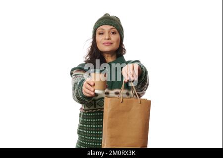 Schöne Frau hält Einwegbecher mit Heißgetränk zum Mitnehmen und Papierbeutel mit frischem, gesundem Essen. Lieferservice Stockfoto