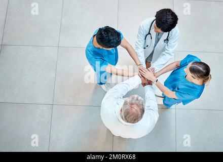 Nehmen wir die Hände in die Hand. Aufnahmen einer Gruppe von Ärzten, die ihre Hände in einem Krankenhaus stapeln. Stockfoto