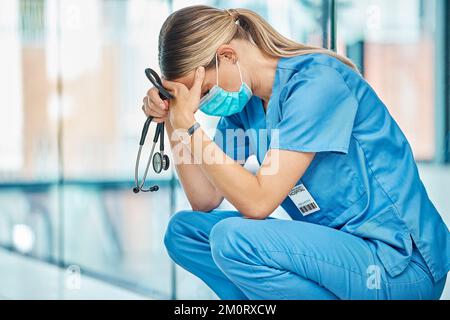 Burnout tritt ein. Eine junge Ärztin, die müde aussieht, während sie in einem modernen Krankenhaus arbeitet. Stockfoto